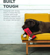 Dog chewing the Fire Hose Fetch Toy labeled "Built Tough." Made for strong biters using firehose material and double-stitched seams. Perfect for fetch, tug, and supervised chewing. Durable and engaging for active pups.