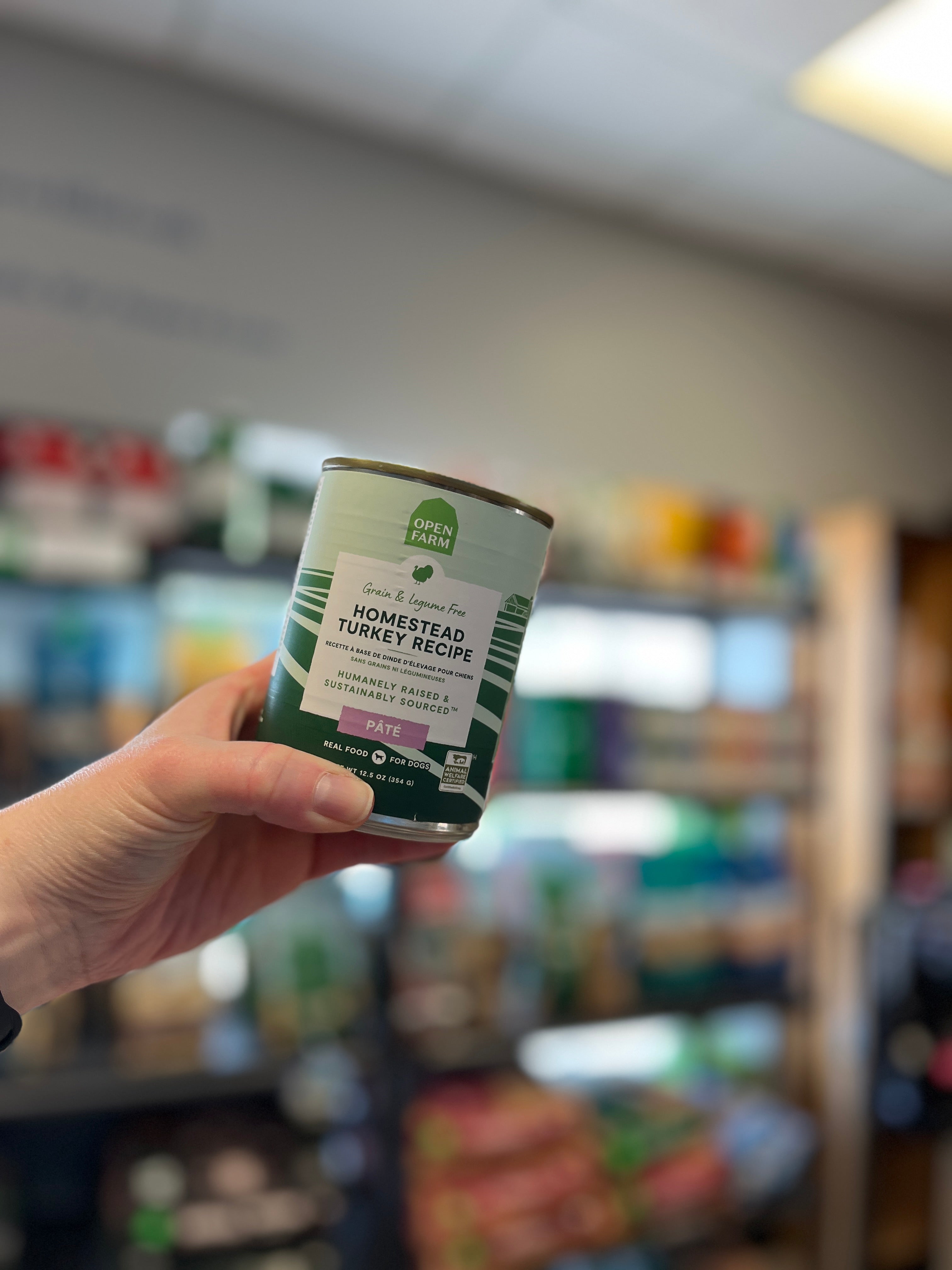 Hand holding a can of Open Farm Homestead Turkey Pâté, highlighting the product's label and ethical sourcing promise.