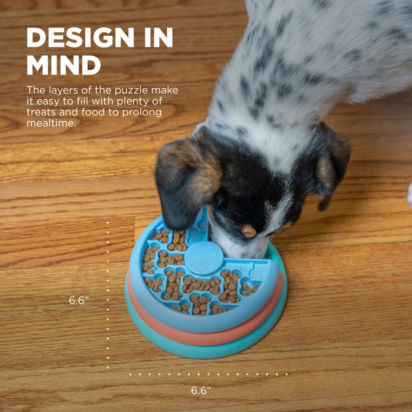 A puppy enjoying the puzzle feeder, with dimensions displayed for size reference.