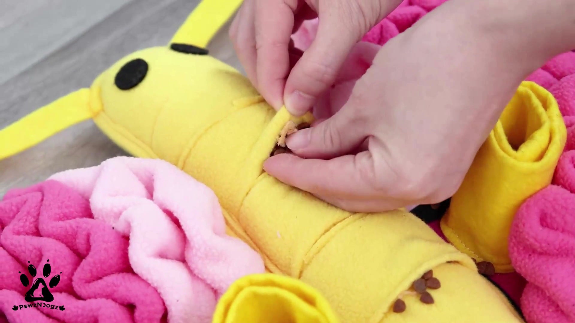 A hand hiding a treat inside the folds of the snuffle mat, showcasing how it encourages problem-solving and mental stimulation.