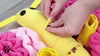 A hand hiding a treat inside the folds of the snuffle mat, showcasing how it encourages problem-solving and mental stimulation.