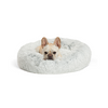 A small dog comfortably curled up in the Best Friends by Sheri Calming Donut Dog Bed in Frost color, showcasing its cozy design.