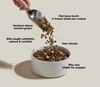 Scoop of puppy kibble and freeze-dried raw pieces falling into a bowl with visual highlights of DHA for brain health, Omega fatty acids for skin and coat, and protein for muscle development.