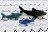Fluff & Tuff Shark Family size comparison featuring Mac the Shark (Large), Tank the Shark (Small), and Baby Bruce the Shark (Extra Small), showcasing the range of plush shark dog toys available for different breeds, play styles, and life stages, all crafted with ultra-soft fabric, reinforced Tuffweb™ mesh lining, embroidered safety details, durable construction, and machine-washable materials for fetching, carrying, cuddling, and interactive play.