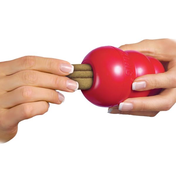 Image of a hand placing a KONG Ziggie into a KONG Classic toy, demonstrating how the chew can be used to enrich playtime while promoting oral hygiene.