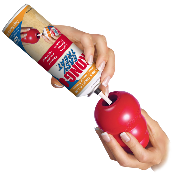 Image showing a hand dispensing KONG Easy Treat Bacon & Cheese into a KONG toy, highlighting the easy nozzle design for clean and controlled stuffing.